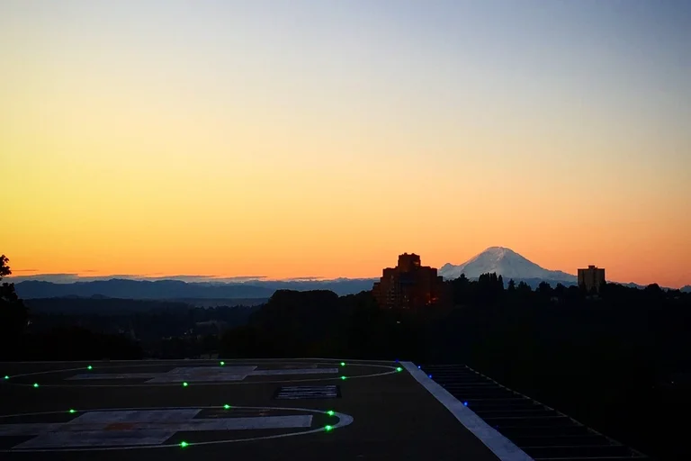 sunset, with a dark view of a helipad in the forefront and mountain in the background