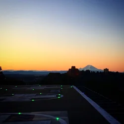 sunset, with a dark view of a helipad in the forefront and mountain in the background