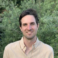 Dr. Judson smiling with a collared shirt and green plant background