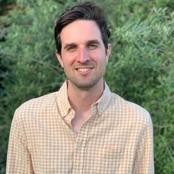 headshot of Seth Judson with a yellow checkered shirt with greenery background